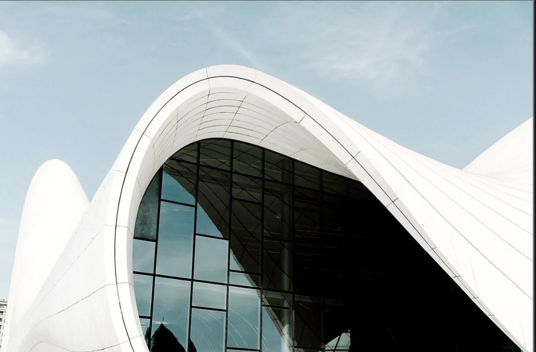 Sculptural white architecture framing a dark glass facade.